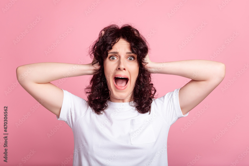 Photo of young woman arms touch head crazy omg unexpected scared isolated over pink color background Photo of young woman arms touch head crazy omg unexpected scared isolated over pink color background