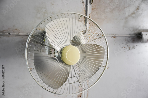 An old electric fan which installed on the ceiling of room, selective and soft focus.