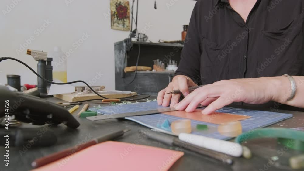 Mid-section close up of unrecognizable female jeweler using ruler and cutting wax while creating mold for ring Mid-section close up of unrecognizable female jeweler using ruler and cutting wax while creating mold for ring