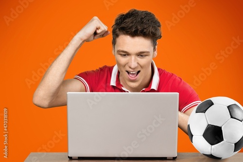 Fotografija Young fun excited man football fan support team with soccer ball use laptop pc c