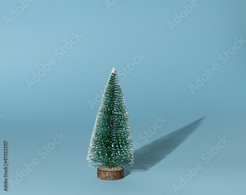 Green Christmas tree on a blue background. Minimal New Year's decoration concept. Creative idea.