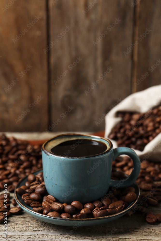 Fototapeta premium Cup of aromatic coffee and beans on wooden table