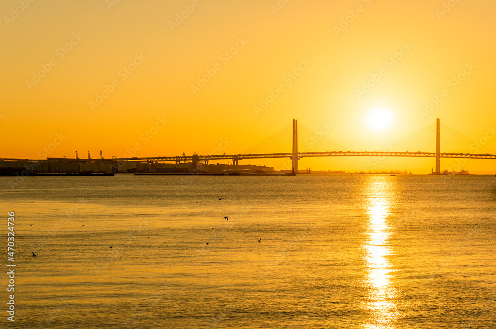 夜明けの横浜ベイブリッジと朝日が反射する海