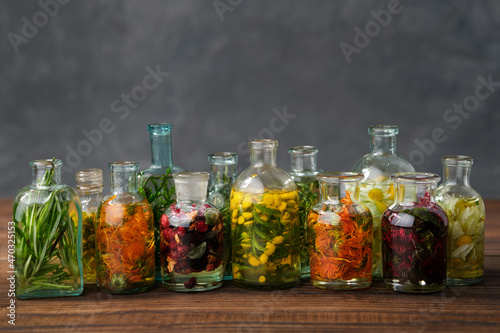 Foto Bottles of essential oil or infusion of medicinal herbs and berries - rosemary, calendula, tansy, thuja, thyme, bergamot, chamomile
