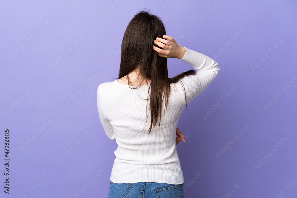 Young Ukrainian woman isolated on purple background in back position and thinking Young Ukrainian woman isolated on purple background in back position and thinking