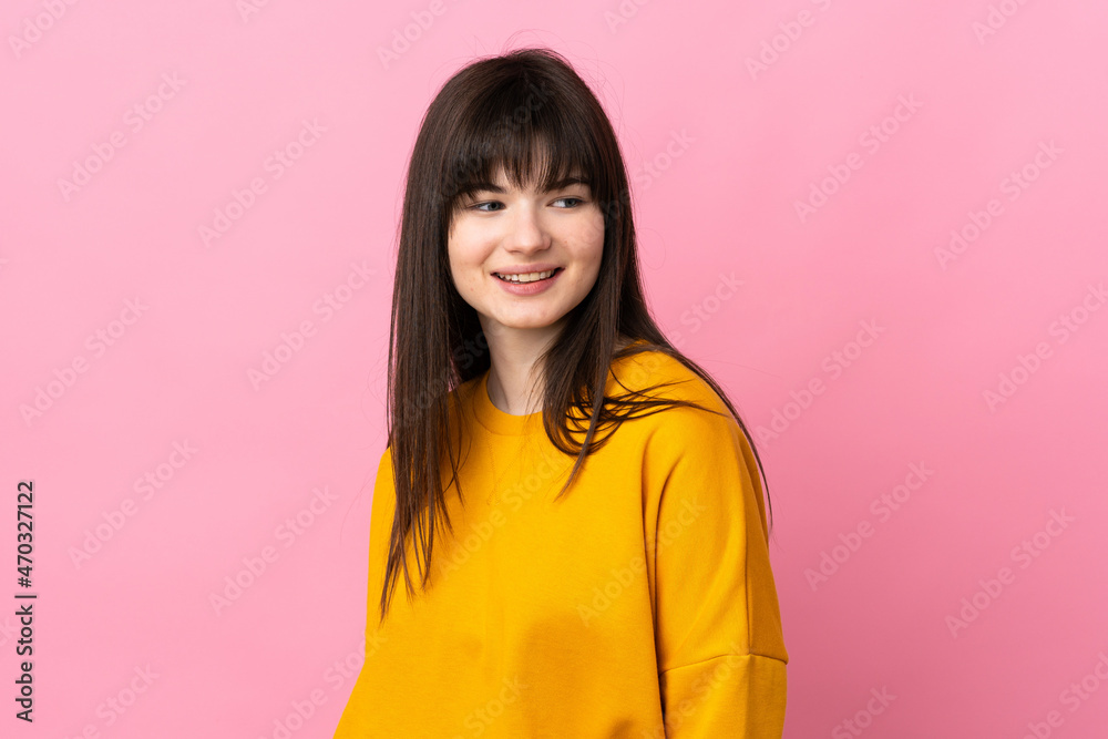 Fototapeta premium Young Ukrainian woman isolated on pink background looking to the side and smiling