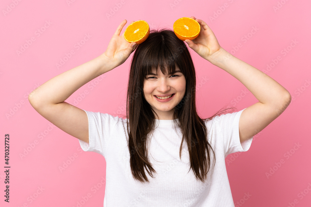 Young Ukrainian woman isolated on pink background holding an orange Young Ukrainian woman isolated on pink background holding an orange