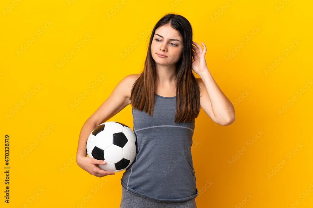 Young football player woman isolated on yellow background having doubts Young football player woman isolated on yellow background having doubts