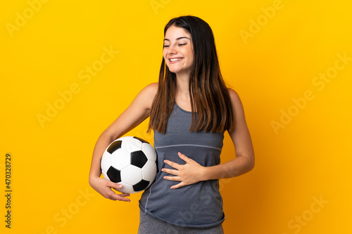 Young football player woman isolated on yellow background smiling a lot © luismolinero