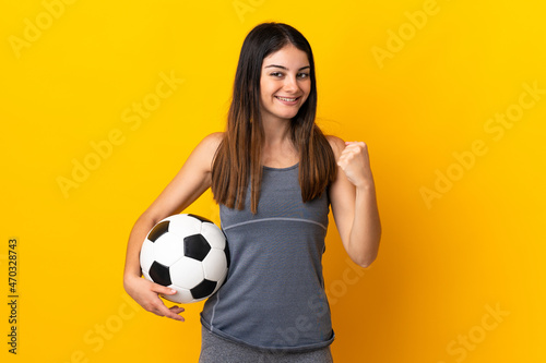 Young football player woman isolated on yellow background celebrating a victory in winner position © luismolinero