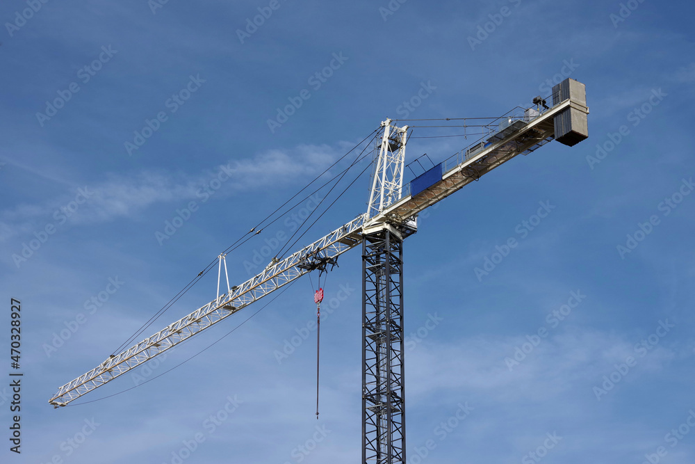 Tall construction crane under blue sky with clouds
