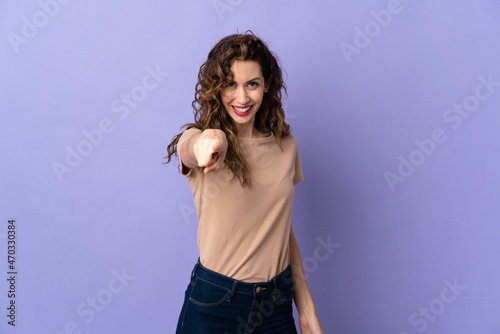 Young caucasian woman isolated on purple background pointing front with happy expression © luismolinero