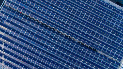 Lots of blue photovoltaic solar panels on the top of the building. Flat densely covered with solar batteries. View from the above.