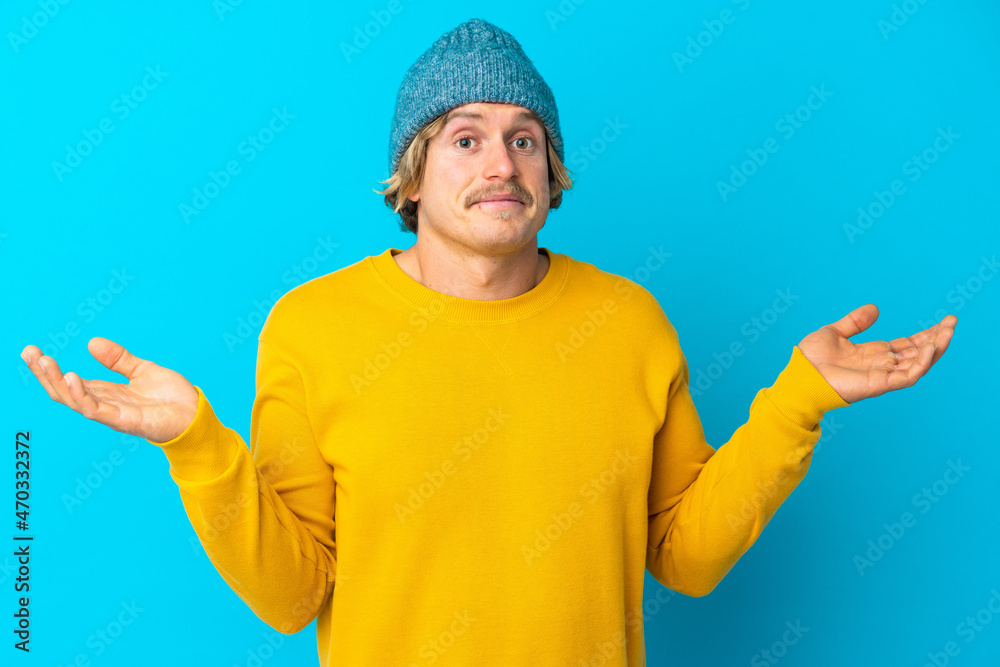 Handsome blonde man isolated on blue background making doubts gesture Handsome blonde man isolated on blue background making doubts gesture