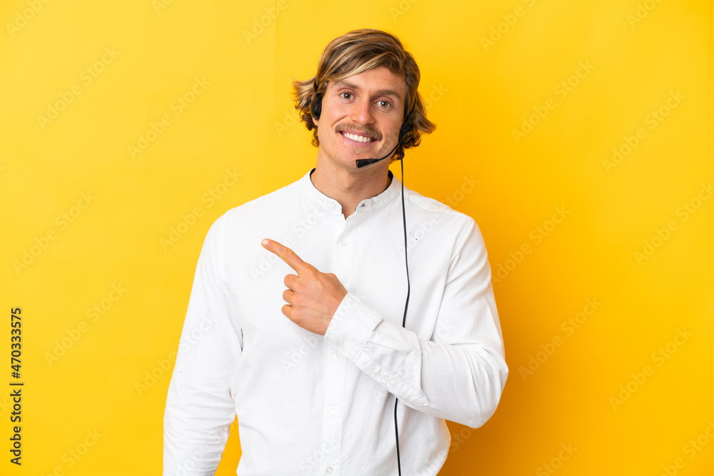 Telemarketer man working with a headset isolated on yellow background pointing to the side to present a product Telemarketer man working with a headset isolated on yellow background pointing to the side to present a product