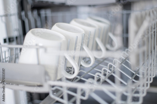 Large white tea cup are stacked in the dishwasher