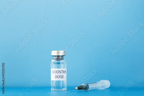 booster dose, vial with a vaccine against coronavirus and a syringe on a blue background with a copy space,third stage of vaccination
