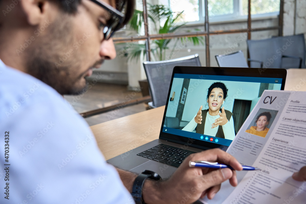 © insta_photos - Indian human resource manager holding cv having virtual job interview conversation with remote female candidate during distant business video call on laptop computer. Online recruitment concept. © insta_photos - Indian human resource manager holding cv having virtual job interview conversation with remote female candidate during distant business video call on laptop computer. Online recruitment concept.
