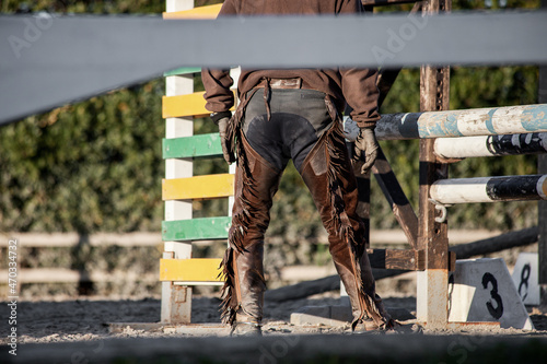 Ranch life, rear view of a cowboy wearing chaps while working in paddock photo