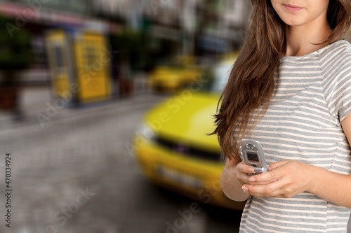 Smartphone or phone in hands on a blurred background of a yellow taxi service car.