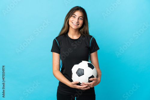 Young football player woman isolated on blue background posing with arms at hip and smiling