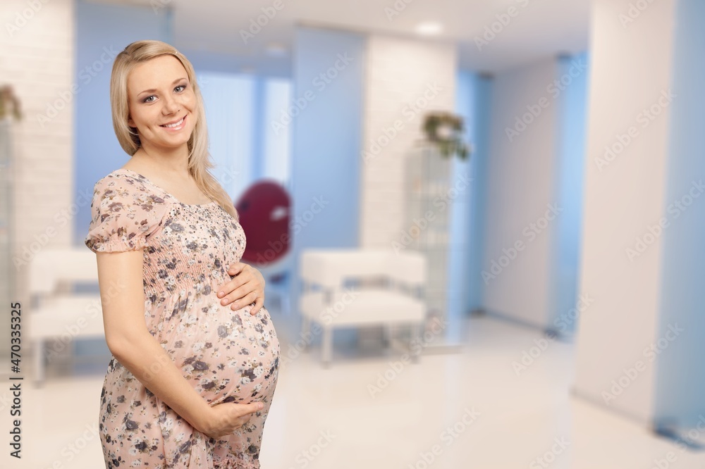 Side view of a beautiful pregnant woman standing near window at home