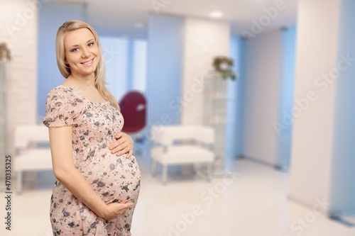 Side view of a beautiful pregnant woman standing near window at home