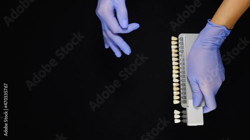 Vita tooth color scale in dental clinic in female hands shot on black background. palette with teeth of different colour. tooth color sample to determine shade of patient teeth. Vertical footage