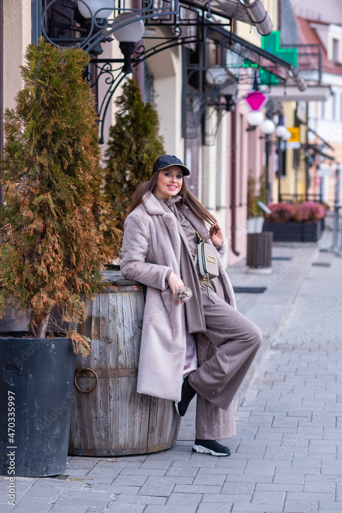 beautiful caucasian girl walks in the city in winter in a fur coat and hat