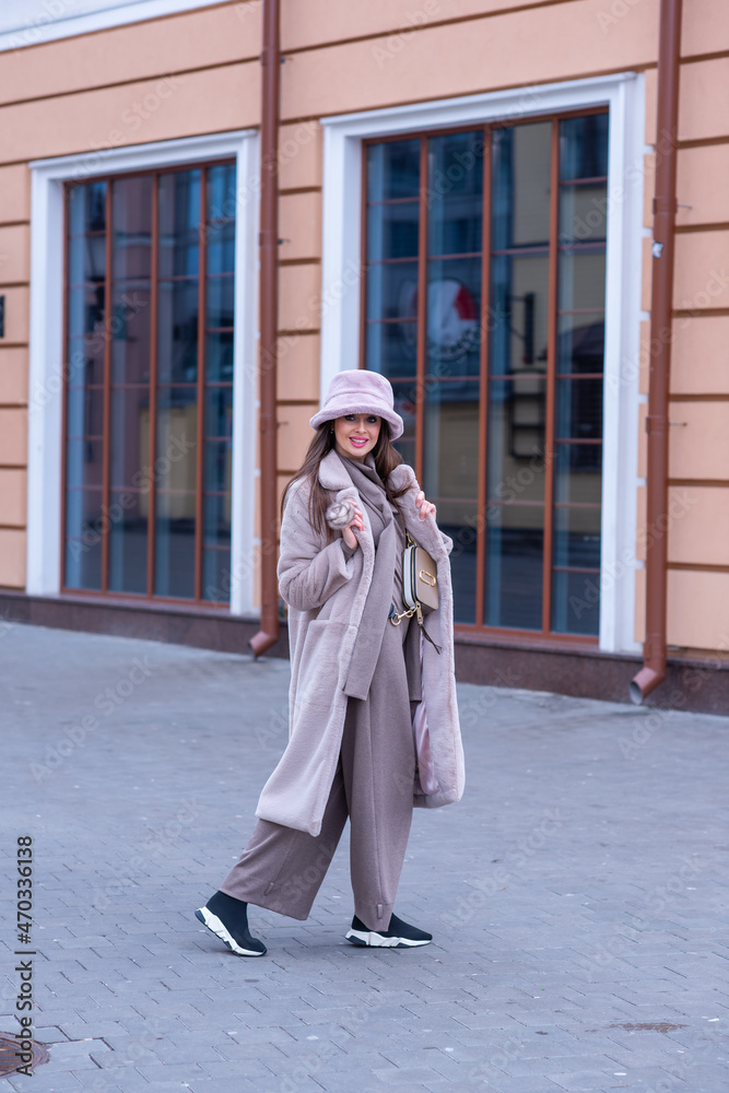 Naklejka premium beautiful caucasian girl walks in the city in winter in a fur coat and hat