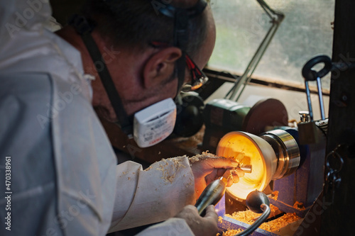 A wooden bowl being turned by a man on a woodturning lathe.A craftsman at work.Sawdust is flying. photo