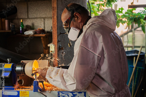A wooden bowl being turned by a man on a woodturning lathe.A craftsman at work.Sawdust is flying. photo
