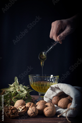 Walnut kernels, whole walnuts, nuts in a bag. Dried linden flowers. Honey. Dark wood background