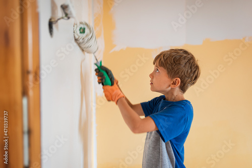 Young boy paints a wall in a room with a roller - intentional blurred motion photo