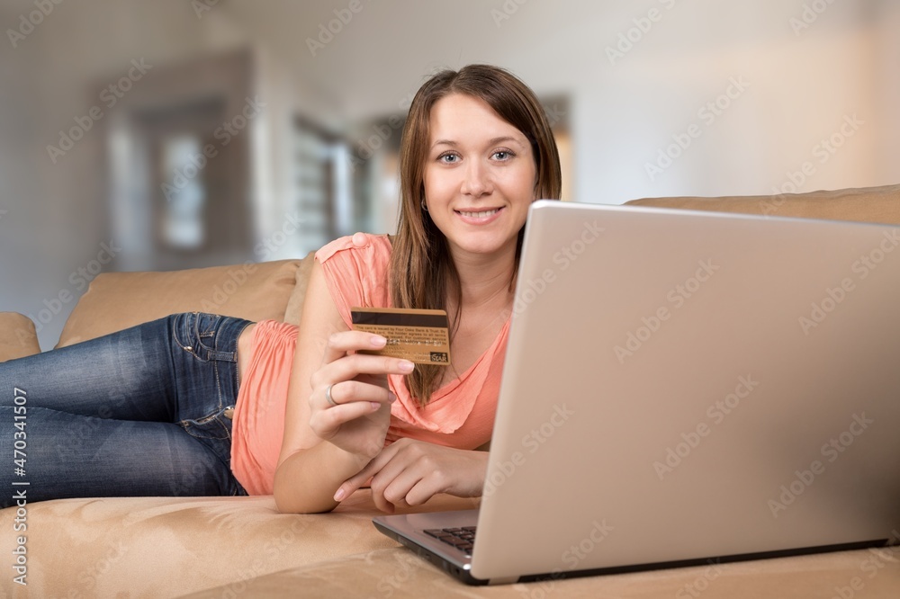 Naklejka premium Happy young woman shopping online, paying bills with credit card
