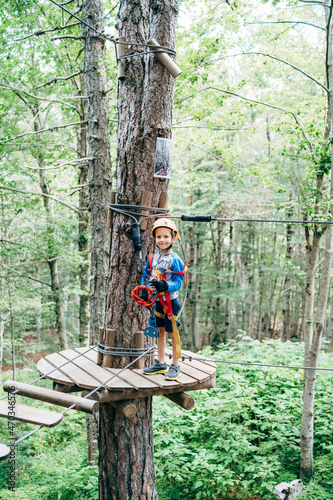Boy in protective gear stands on a wooden platform in front of the agility bridge