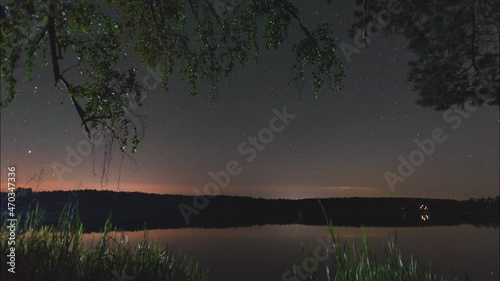 Timelapse of the movement of stars over a lake in a forest on a summer night in Russia