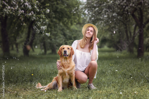 beautiful caucasian girl with golden retriever dog in blooming gardens
