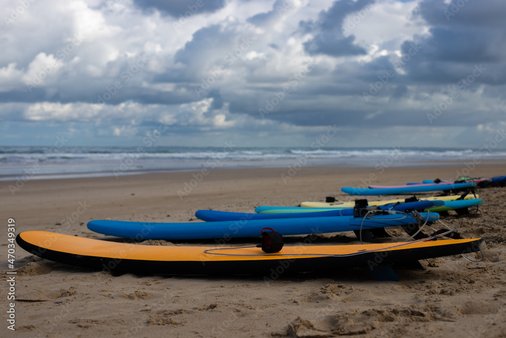 surf boards from a surf school at the beach of soulac-sur-mer at the atlantic ocean in France with wavy sea and dramatic sky in the background