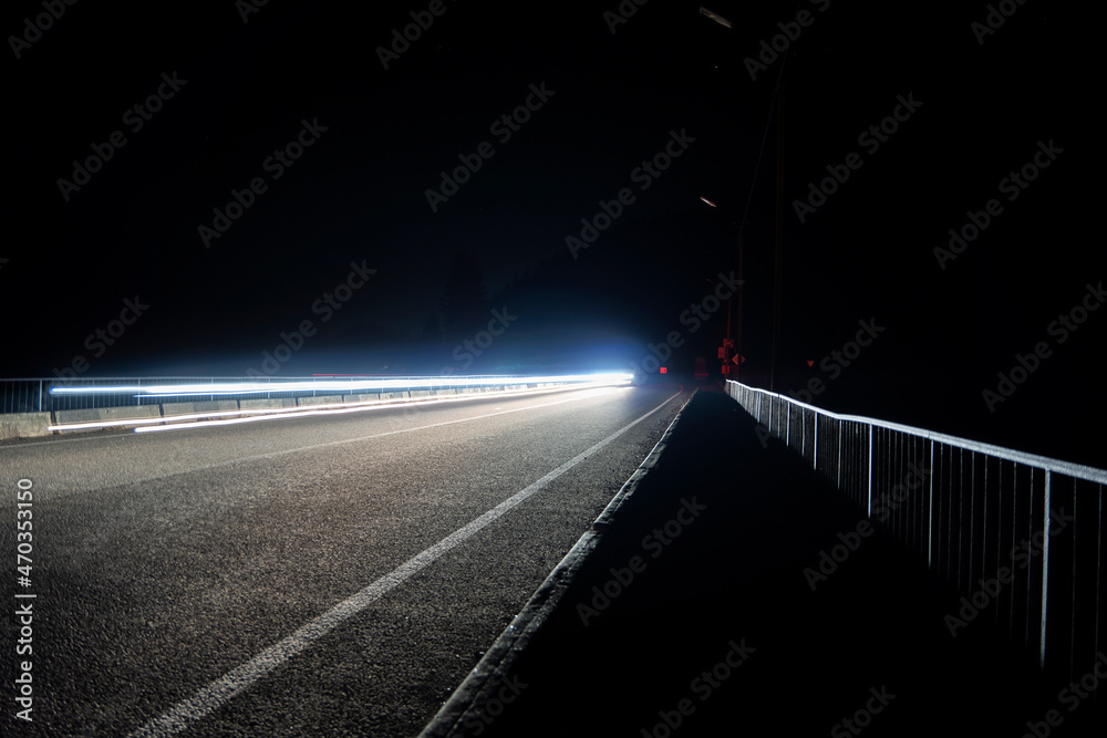 Long exposure of car’s lights on the night winding road with the silhouette of mountains. Long exposure photo of traffic.