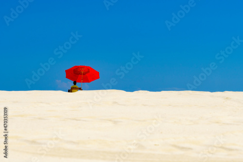 lifeguard in a beach of white sand with a red parasol