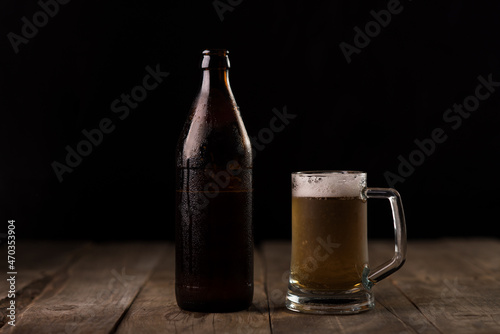 Bottle of craft beer and beer mug on a wooden table