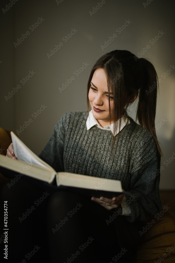 Young woman sitting on sofa and reading book Young woman sitting on sofa and reading book