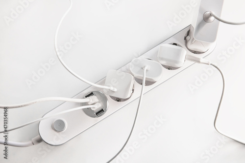 Many chargers plugged into maltiple electrical outlet on white background. Concept of electricity consumption.