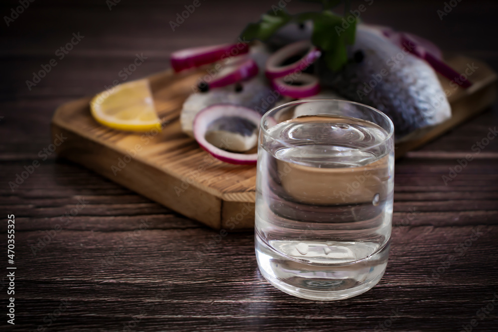 glass of vodka, herring on a wooden background