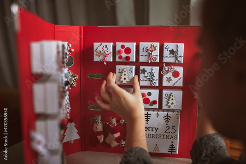Pretty girl opens an original advent calendar like a book made of jewelry boxes and a binder, New Year craft, diy. Magic of moment, seasonal activity. Christmas miracle. Soft focus, depth of field