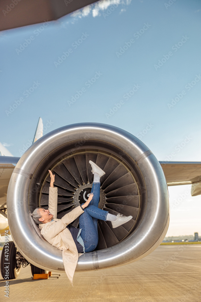 Cheerful women having fun in airplane engine at airport