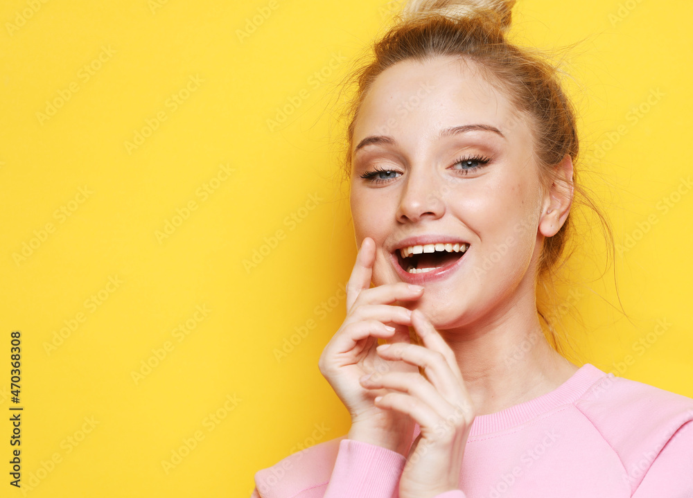 young beautiful female wearing pink sweater looking at camera smiling laughing over yellow background. young beautiful female wearing pink sweater looking at camera smiling laughing over yellow background.