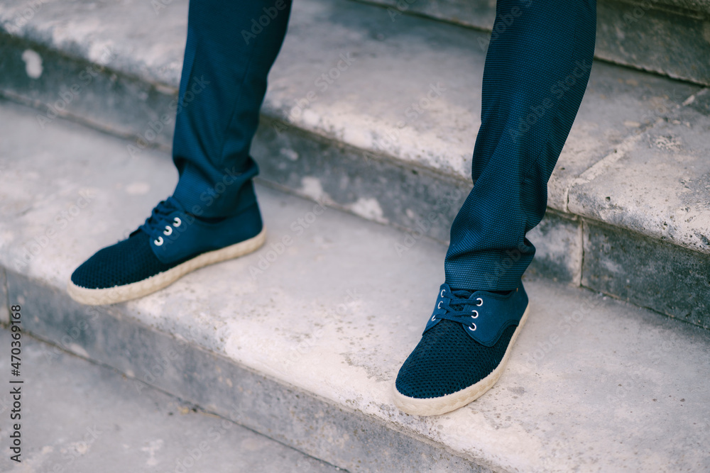 Groom feet in trousers and sneakers on stone steps