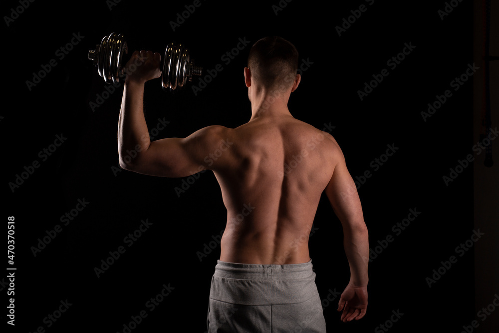 Sport man Standing with Dumbbell in Hand. Man Working out with Dumbbell. Sportsman Back View